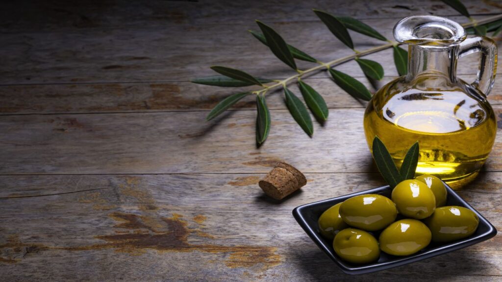 Tasty looking Olives, Extra Virgin Olive Oil for hair and Olive leaf in dark wooden background